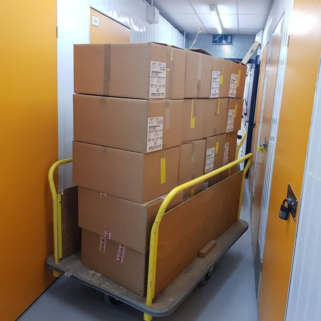There are packed boxes in the trolley near the storage unit.