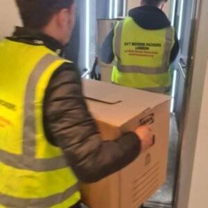 two mans wearing jackets of 24/7 movers packers london carrying boxes from a home and providing removal services