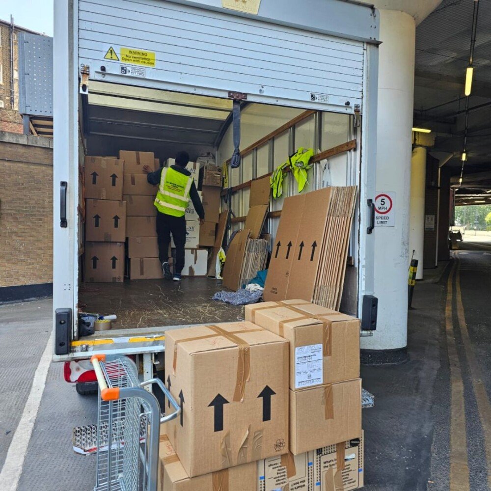 A worker of 24/7 Movers Packers London Company is standing in the van and arranging packed boxes.